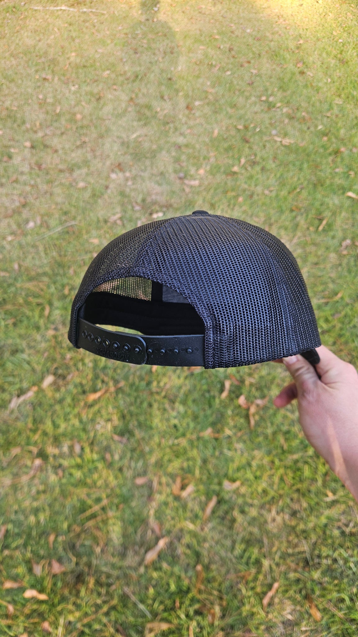 Rear detail of a black Richardson hat showing the mesh back and adjustable snapback closure